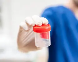 Lab technician holding a 5-panel drug test cup at a DOT testing facility